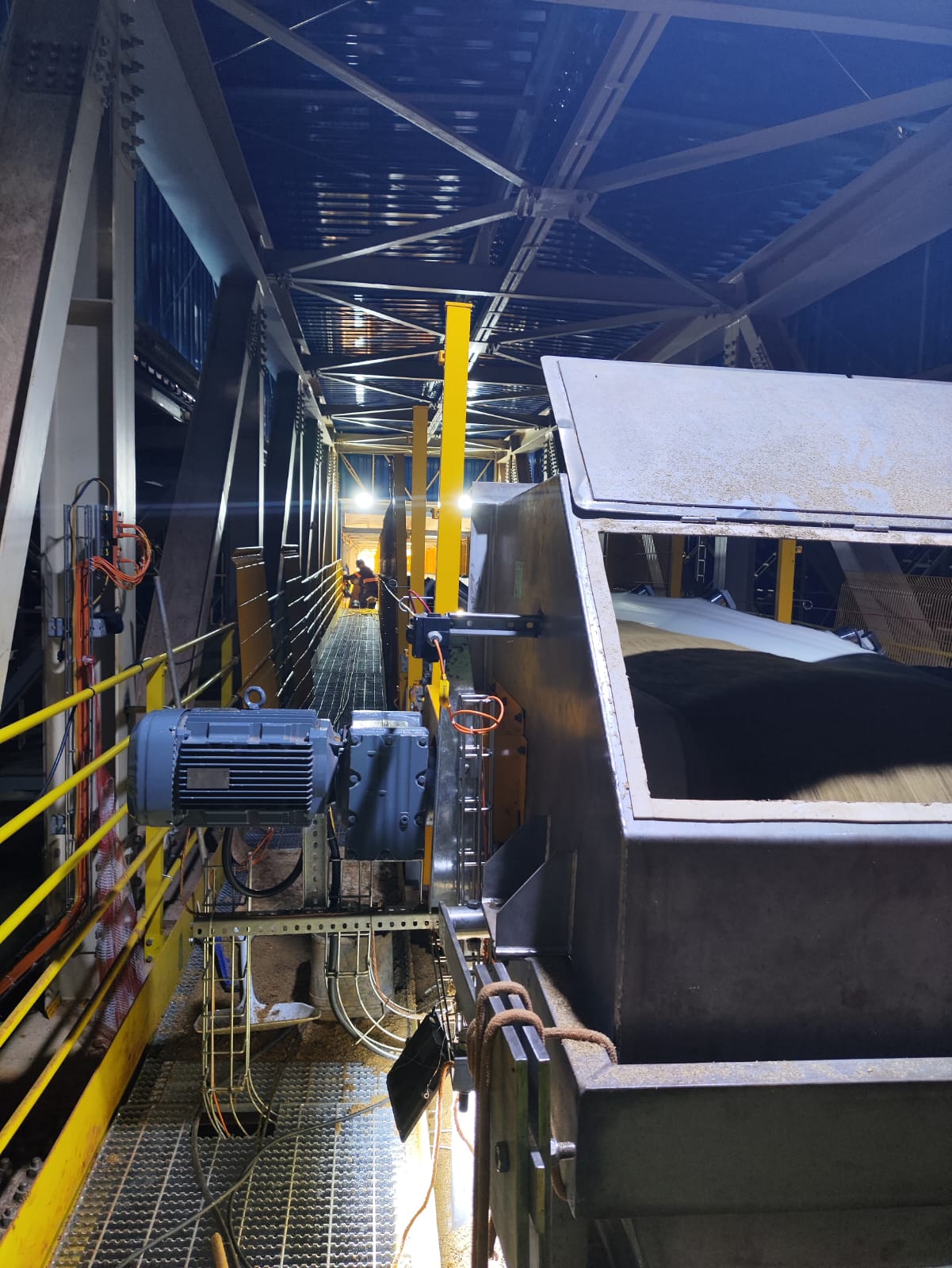 Correia transportadora industrial iluminada em operação noturna dentro de planta