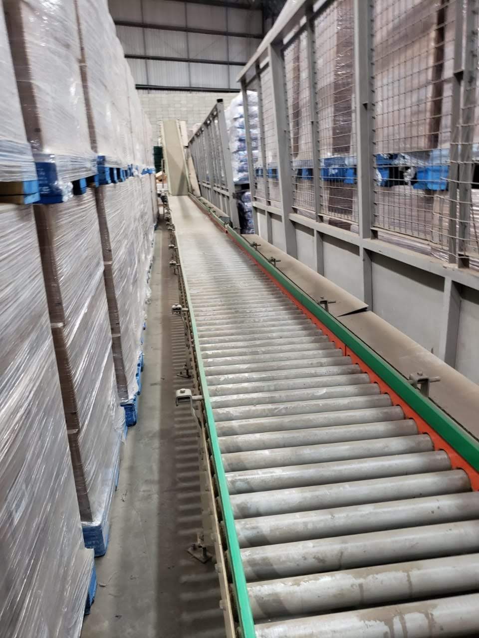 Esteira de rolos industrial instalada em corredor de galpão logístico